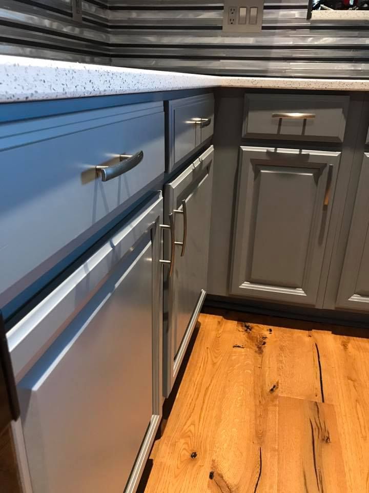 A kitchen with gray cabinets and wooden floors