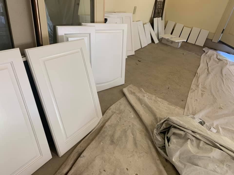 A bunch of white cabinet doors are sitting on the floor