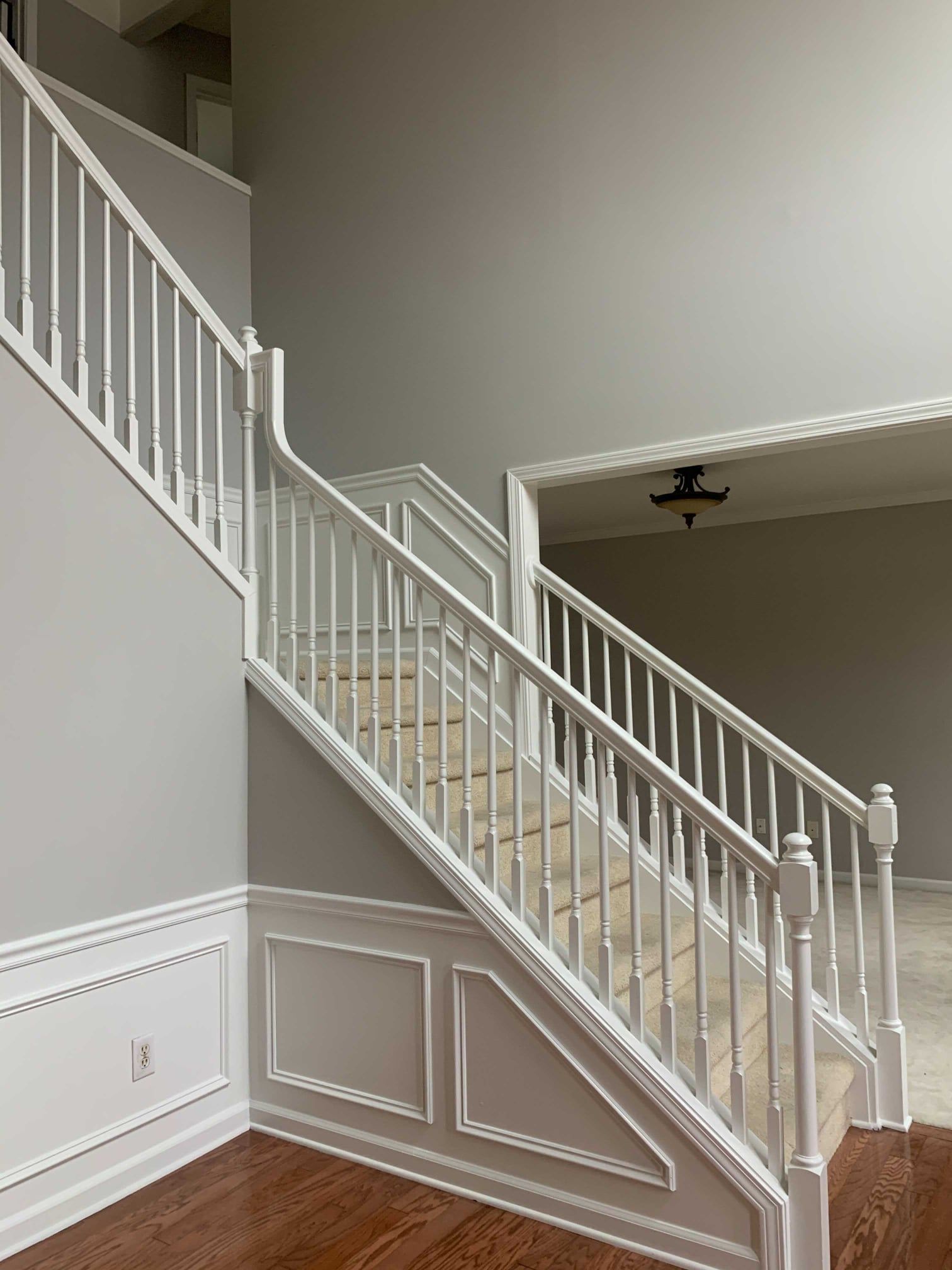 There is a staircase in the middle of the room with a white railing.