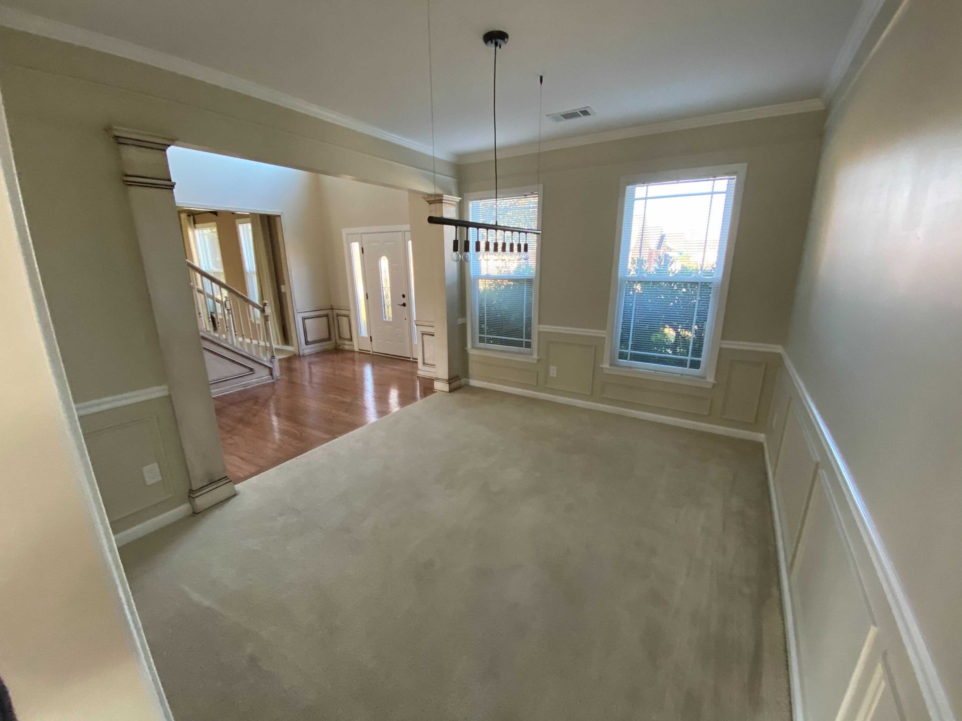 An empty living room with a chandelier hanging from the ceiling.