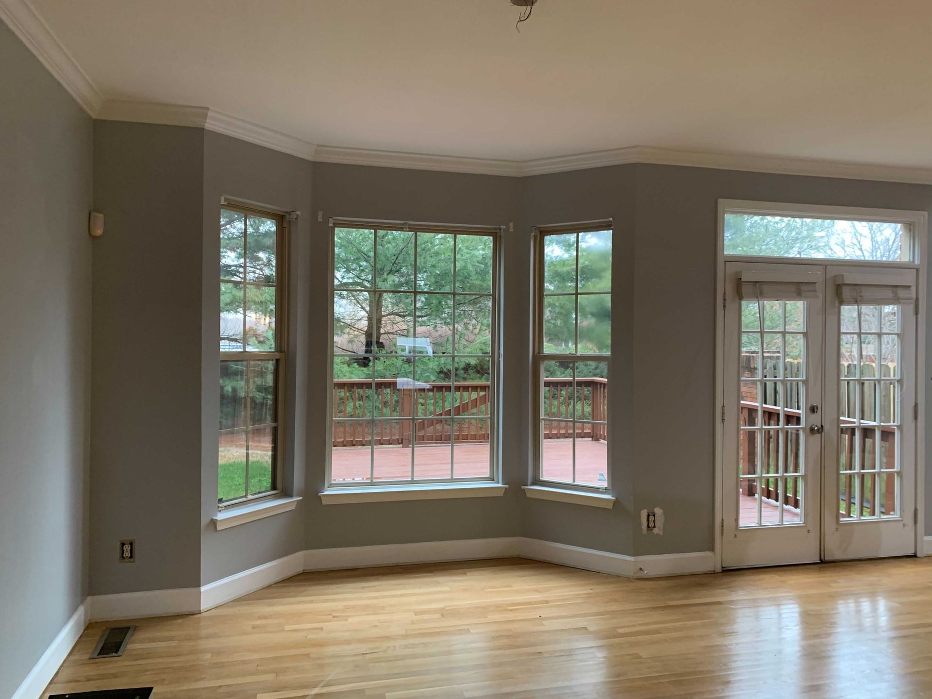An empty living room with hardwood floors and lots of windows.