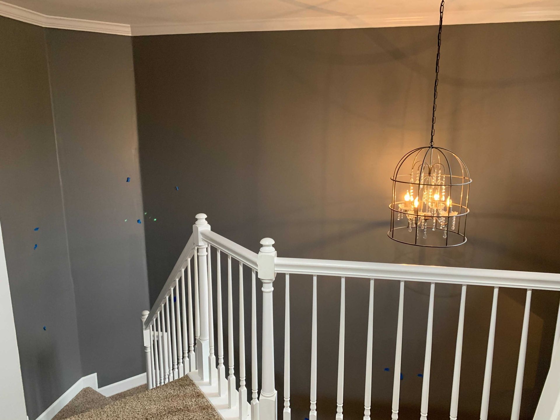 A staircase with a white railing and a chandelier hanging from the ceiling.