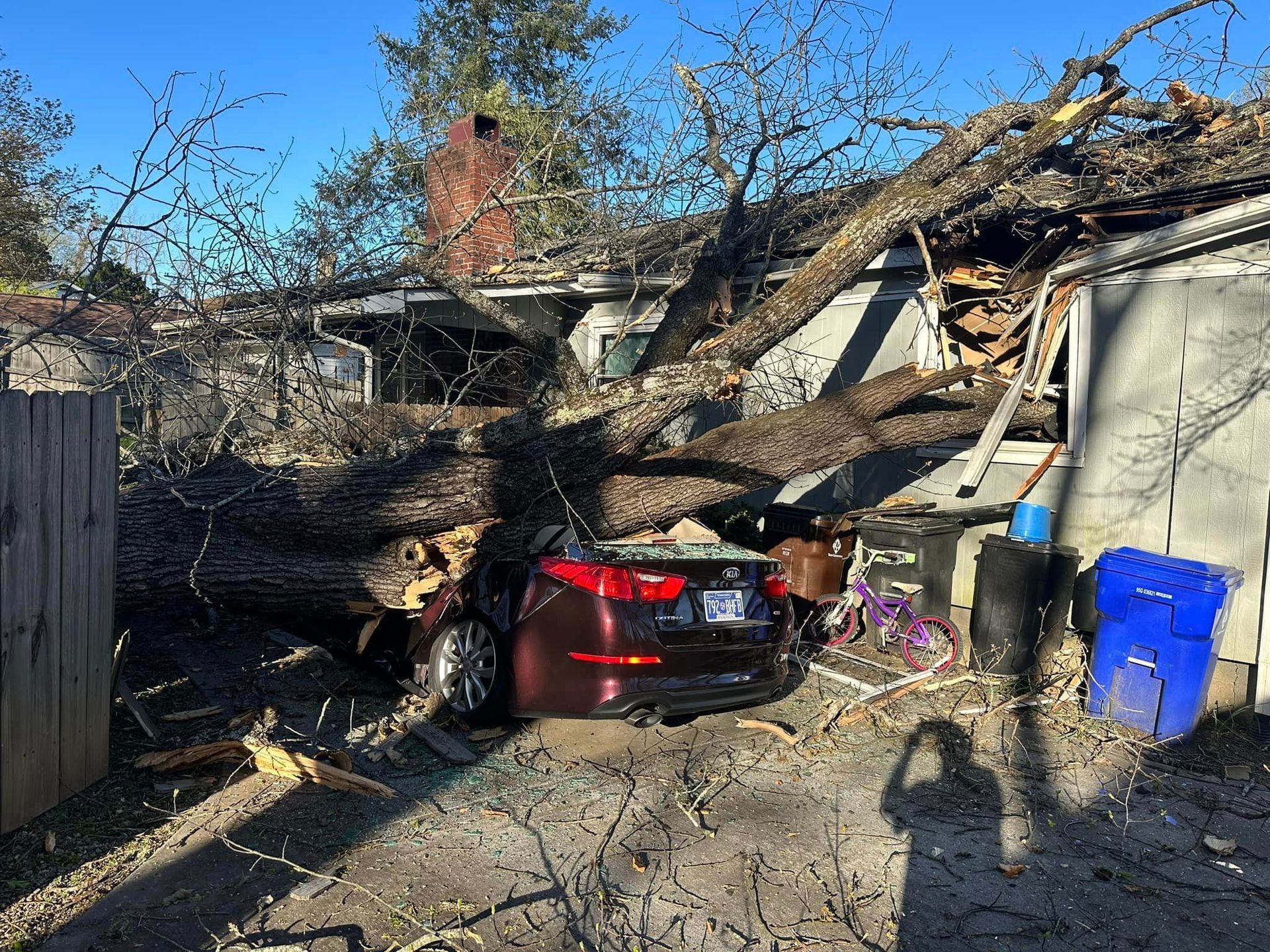 a car is parked in front of a house that has been damaged by a tree
