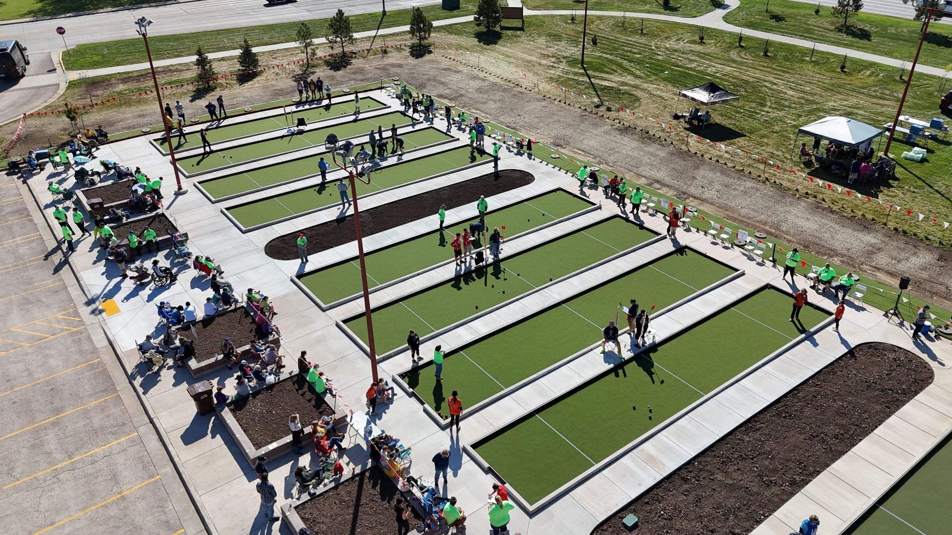 Aerial view of people playing bocce ball on green courts in a park