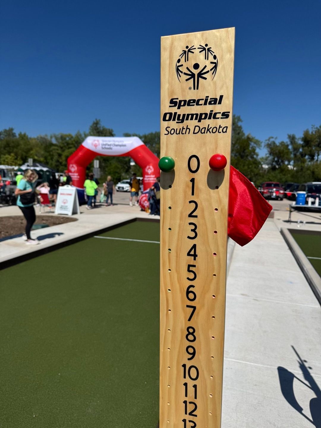 Scoreboard for Special Olympics South Dakota bocce ball game, green and red markers, with arched entrance in the background