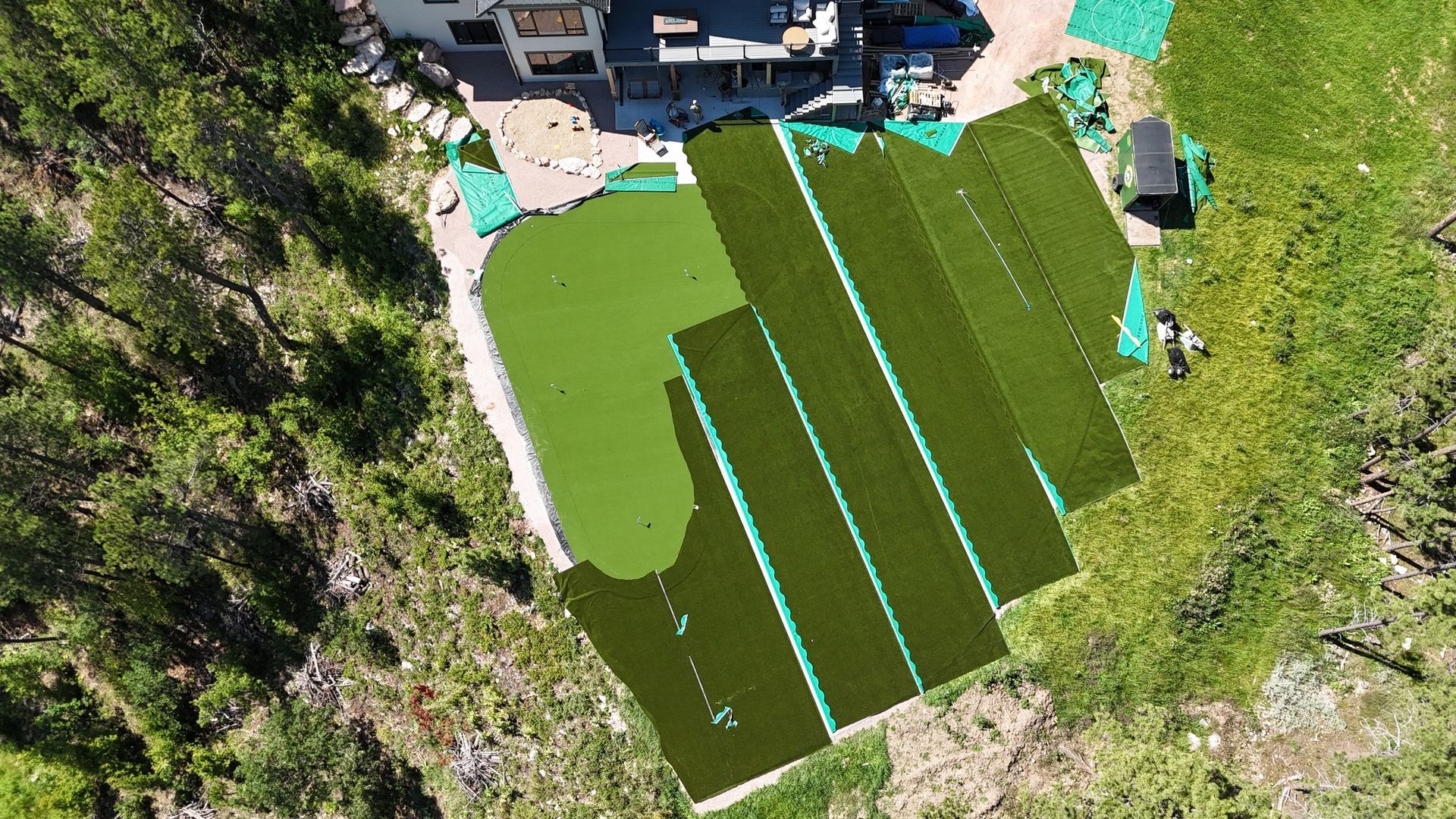 Overhead view of a house with an in-progress artificial turf installation on a sloped yard