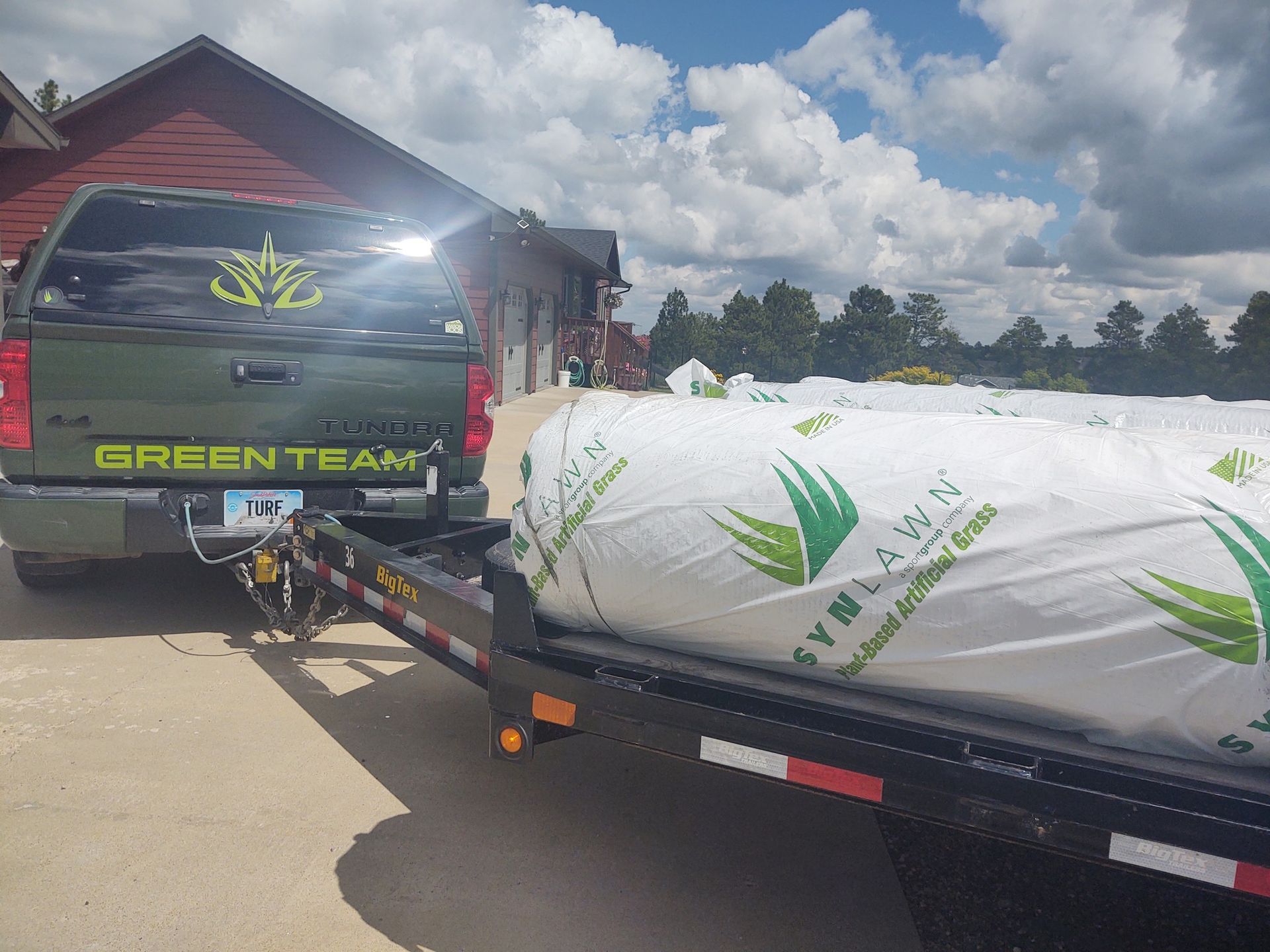 Green truck towing a trailer loaded with rolled sod