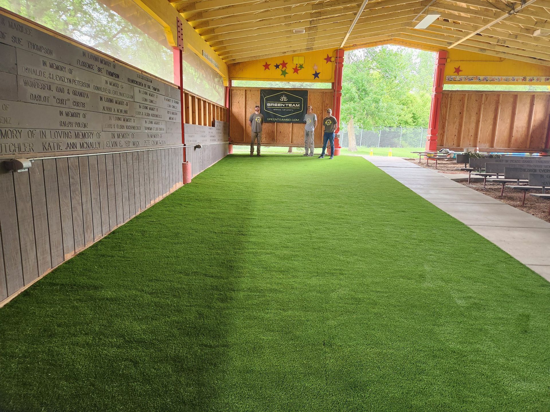 Indoor recreational space with artificial turf, people standing near target
