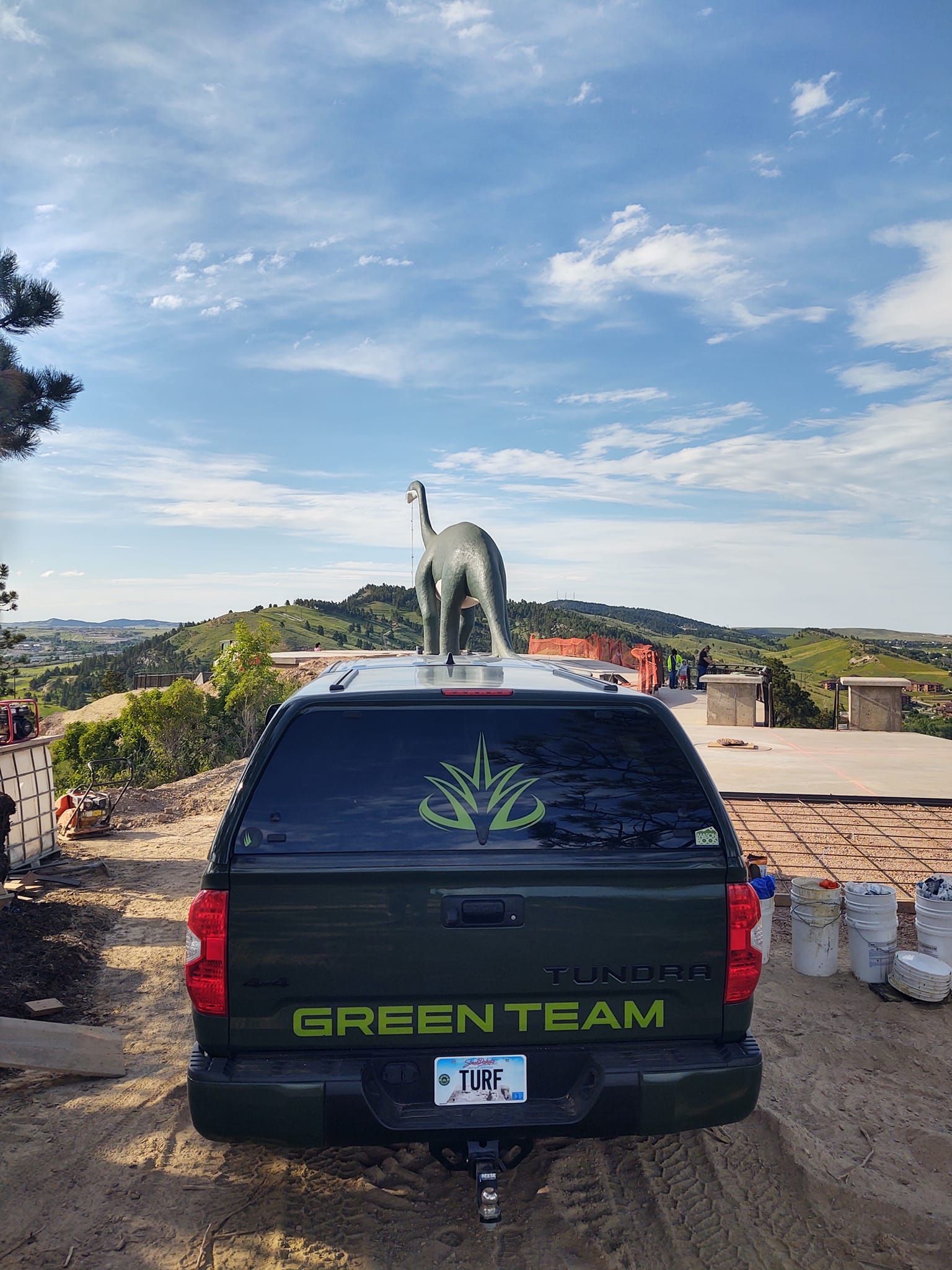 Green truck with a dinosaur statue on top