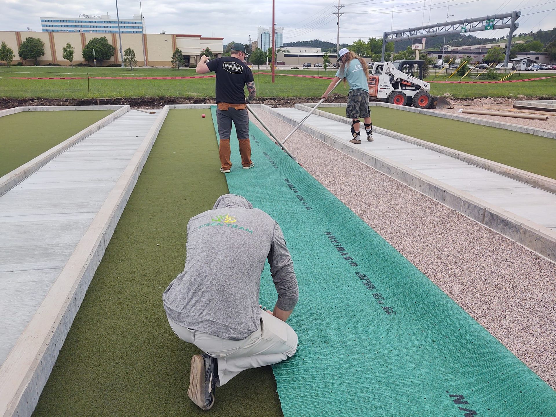 Workers installing artificial turf on a bocce ball court
