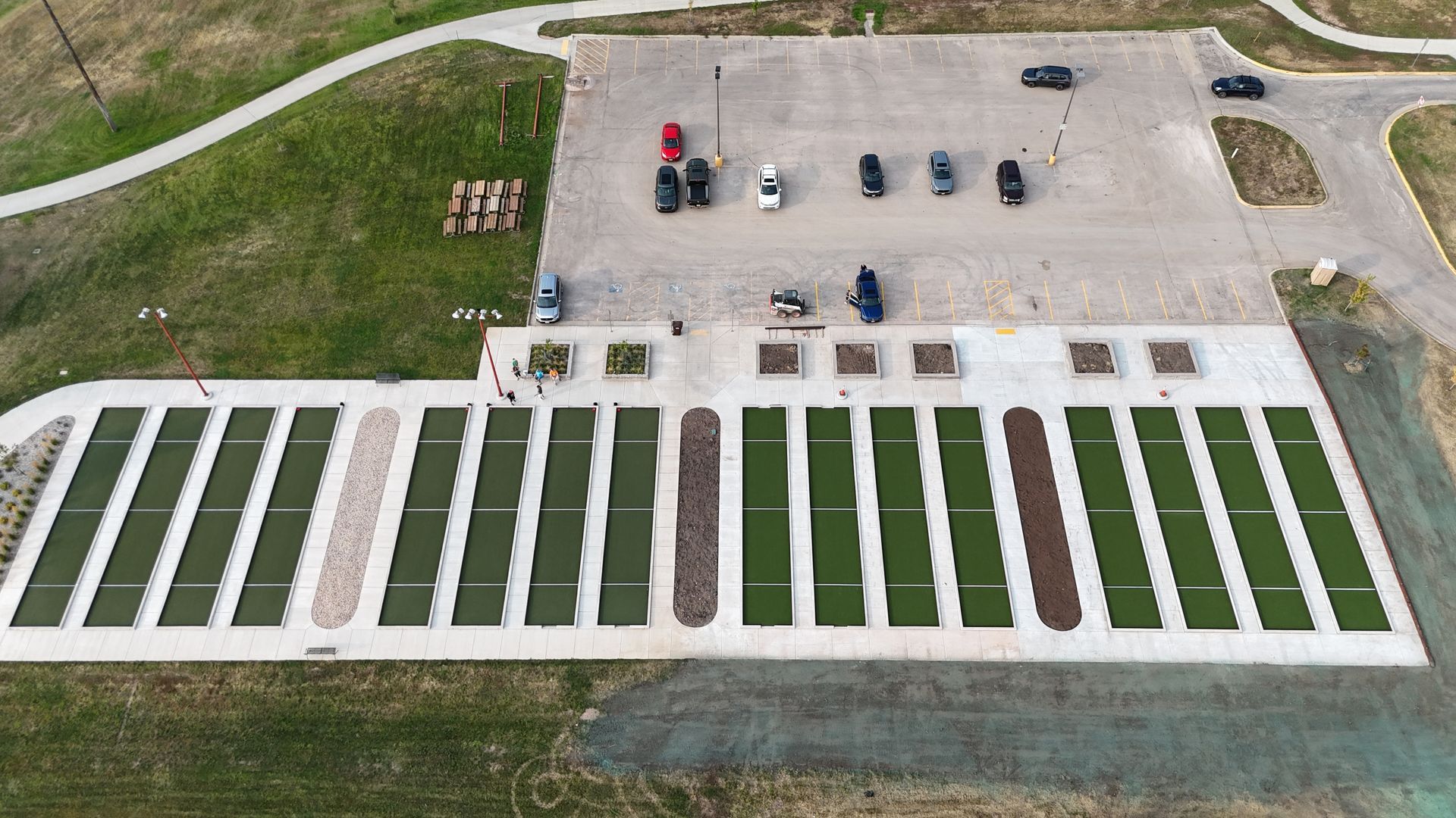 Aerial view of a turfgrass research area with various green plots and parked cars.