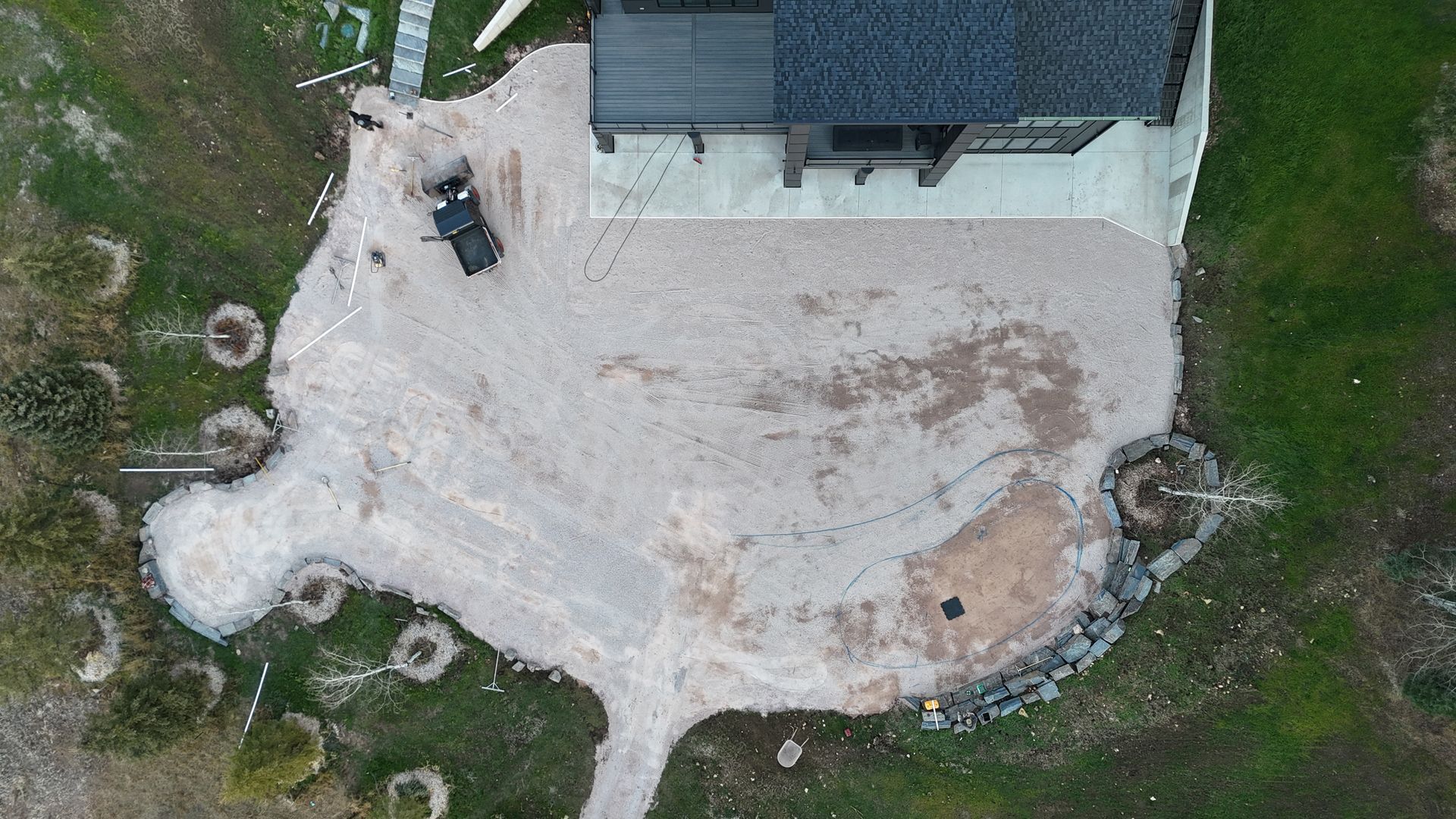 Overhead view of a house with a gravel driveway and surrounding lawn. A black truck is parked on the driveway.