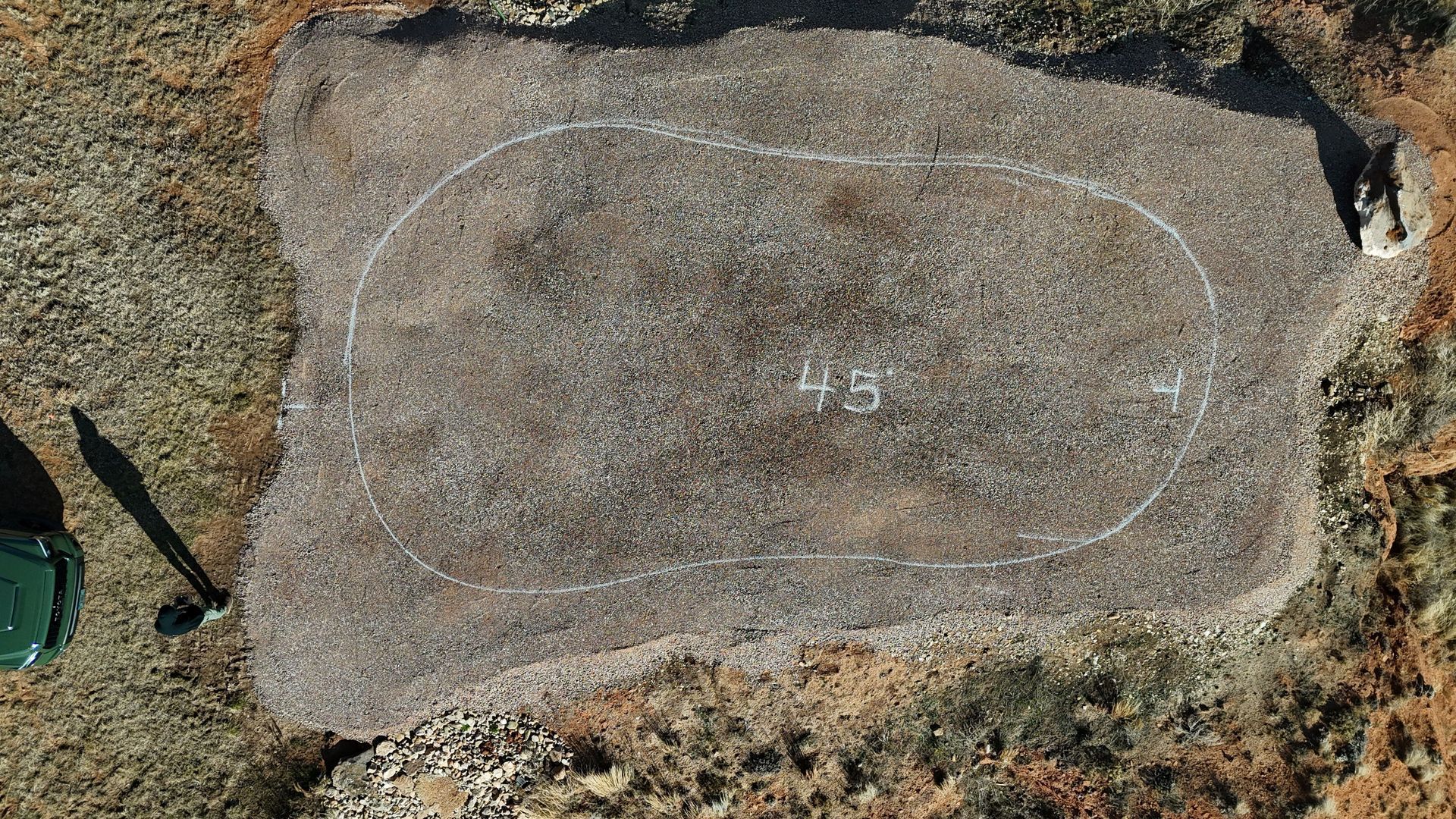Aerial view of a gravel area marked with white lines, measuring 45 x 41 feet. A small, green object and a shadow are visible on the left.