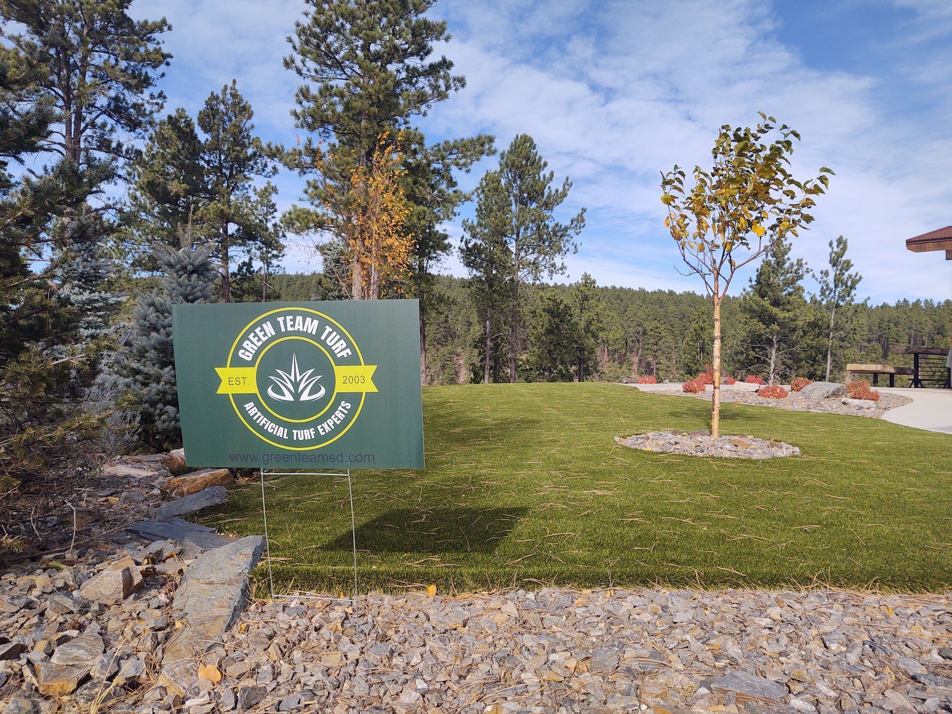 Sign for “Dulac Trading Post” on green lawn, trees and blue sky background.