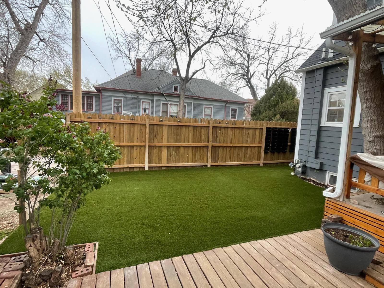 Backyard with a wooden deck, artificial turf lawn, and wooden privacy fence
