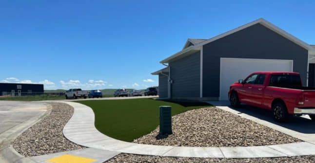 Blue house with red truck parked in front, pathway of green grass and stones