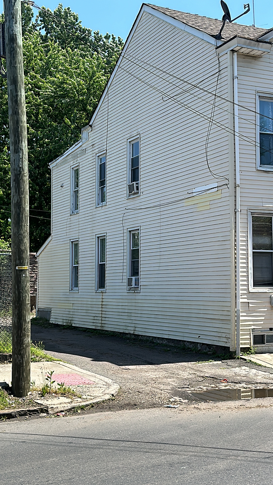 A white house with a lot of windows is sitting on the side of the road