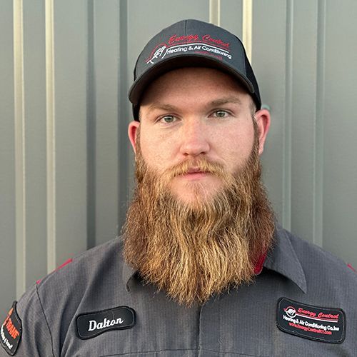 A man with a beard is wearing a hat and a gray shirt.