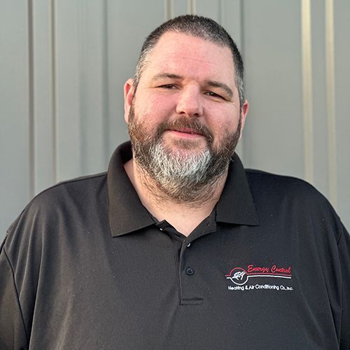 A man with a beard is wearing a black polo shirt.