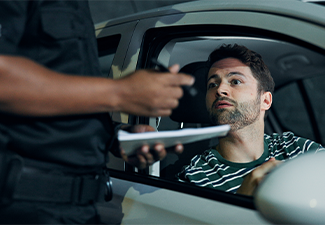 Police officer issuing a ticket to a man stopped in his car through the open window