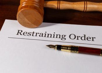 Wooden gavel and pen on a restraining order document