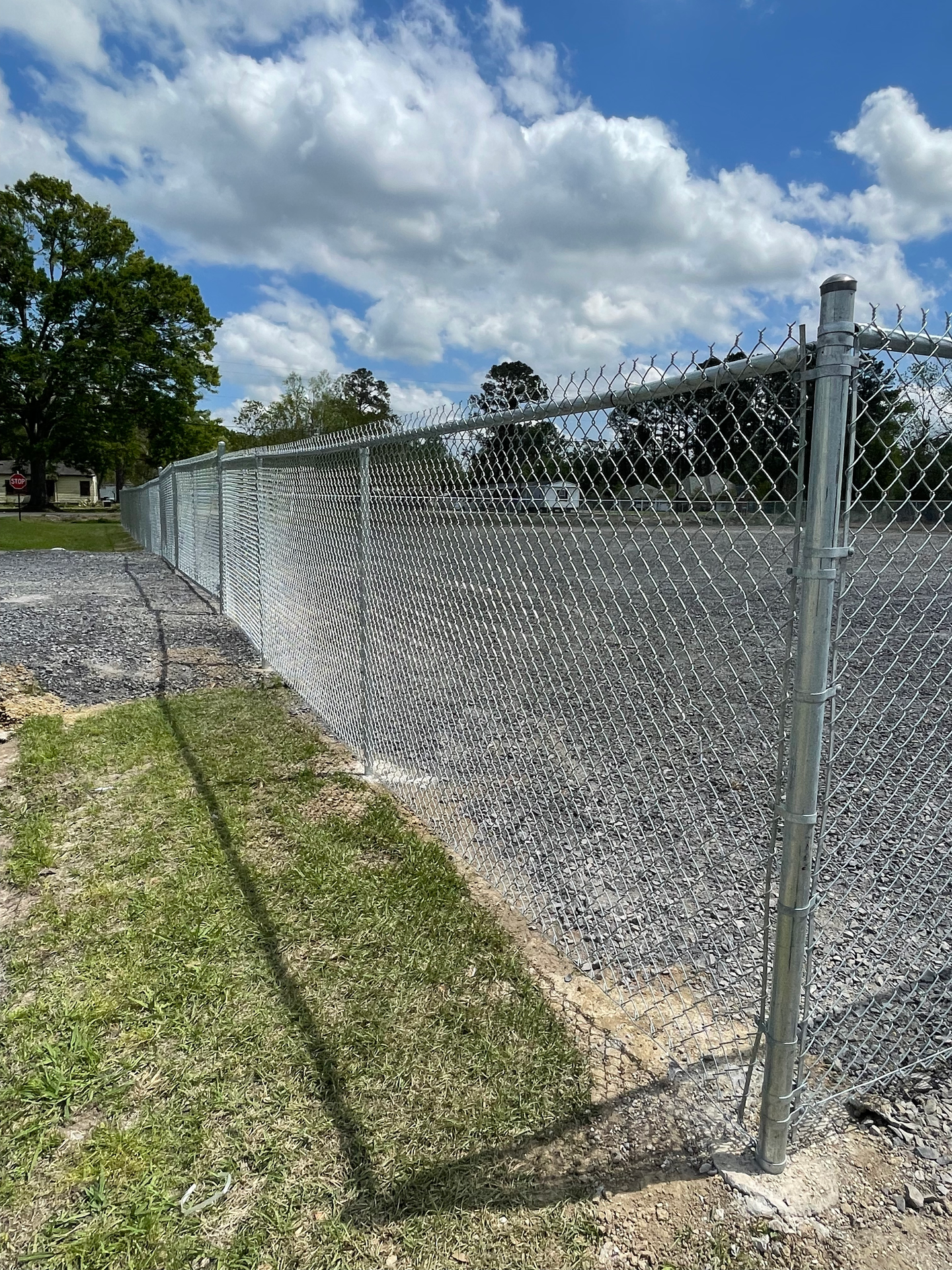 Chain link fence with grass and trees in the background