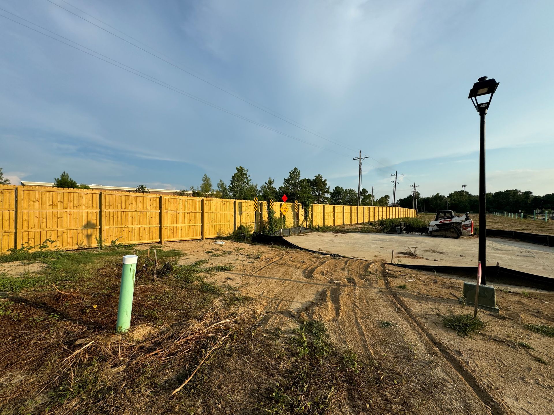 Gravel road with a fence and trees in the background