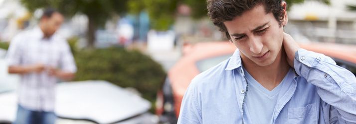 Man in a light blue shirt looking down with a worried expression on a city street