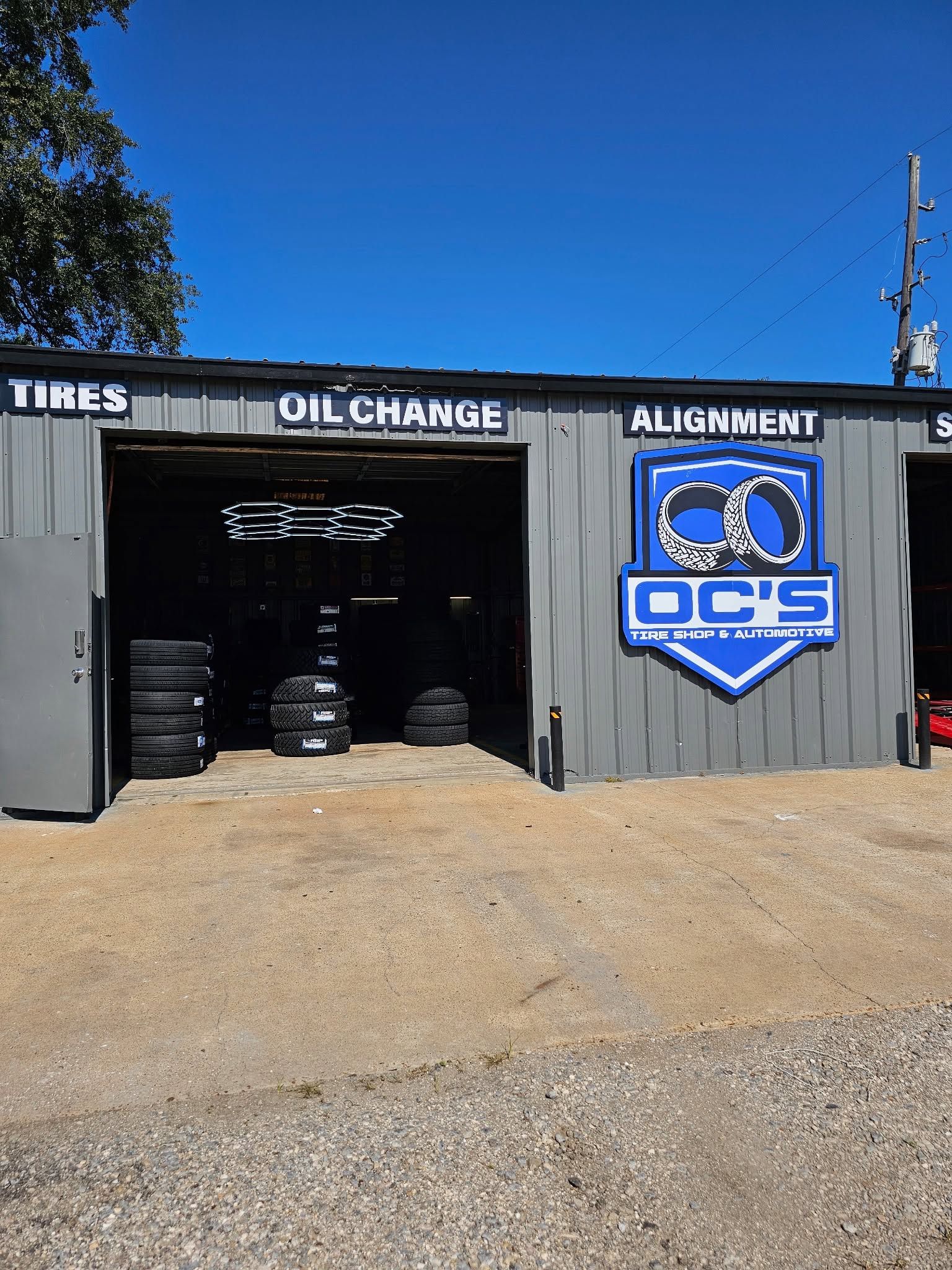 Auto repair shop exterior with tire, oil change, and alignment signs and a blue OC shield logo