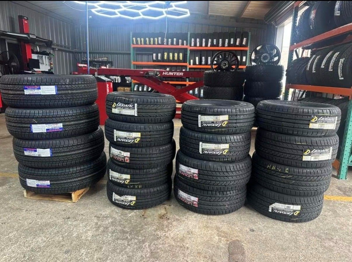 Tire shop interior with stacks of new black tires and red equipment in the background