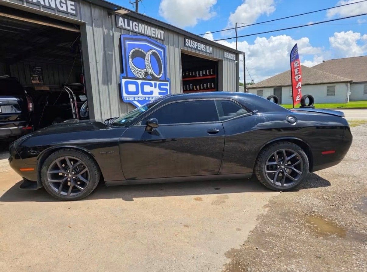 Black sports car parked outside an auto shop on a sunny day