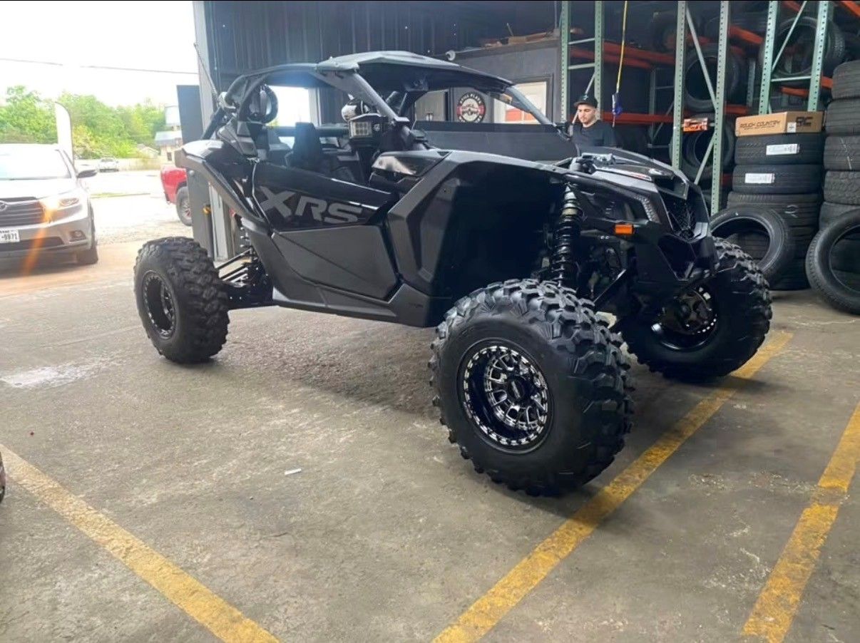 Black off-road side-by-side UTV with large tires parked in a garage or workshop
