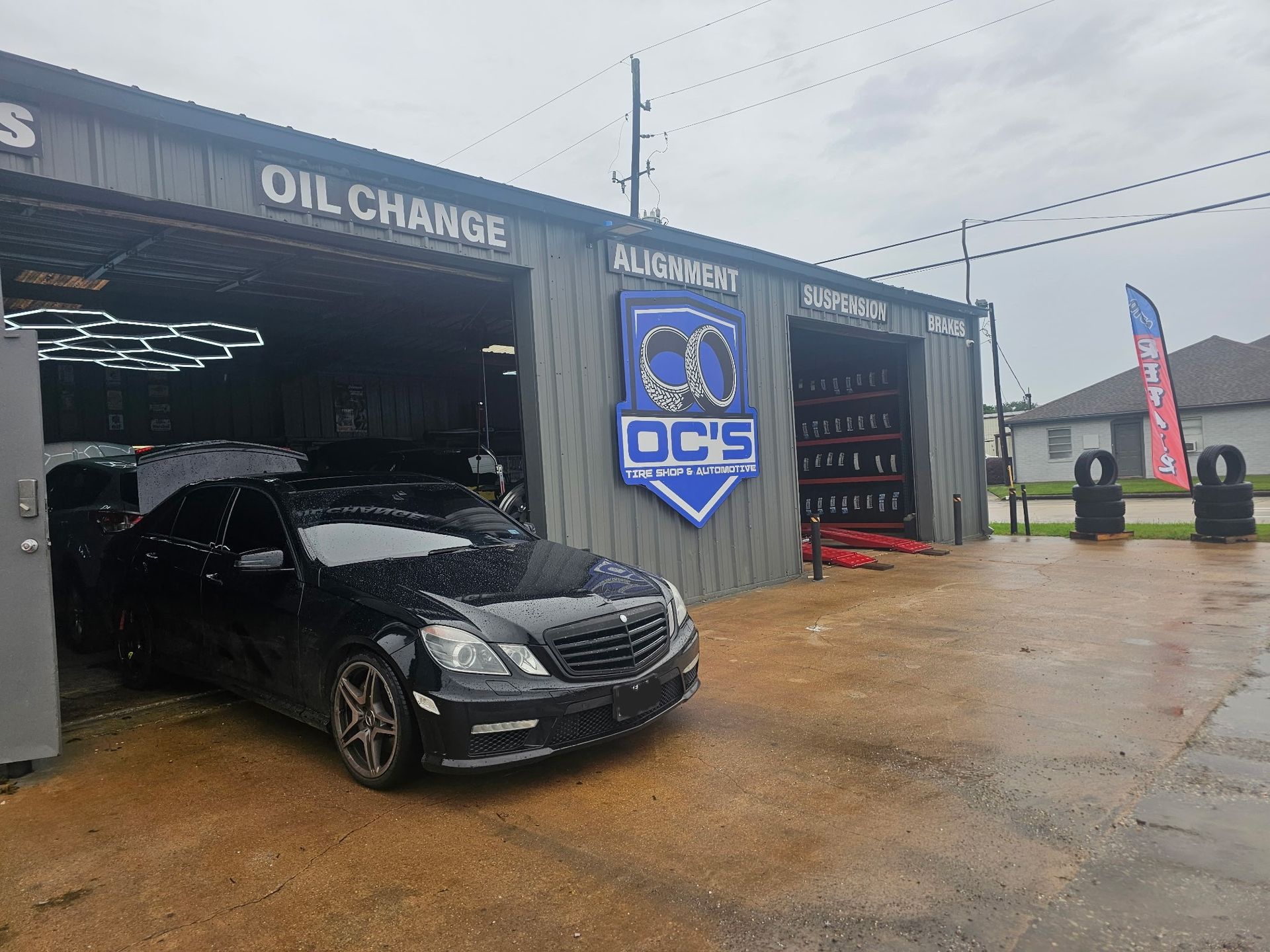 Black sedan parked at an oil change shop entrance on a wet day