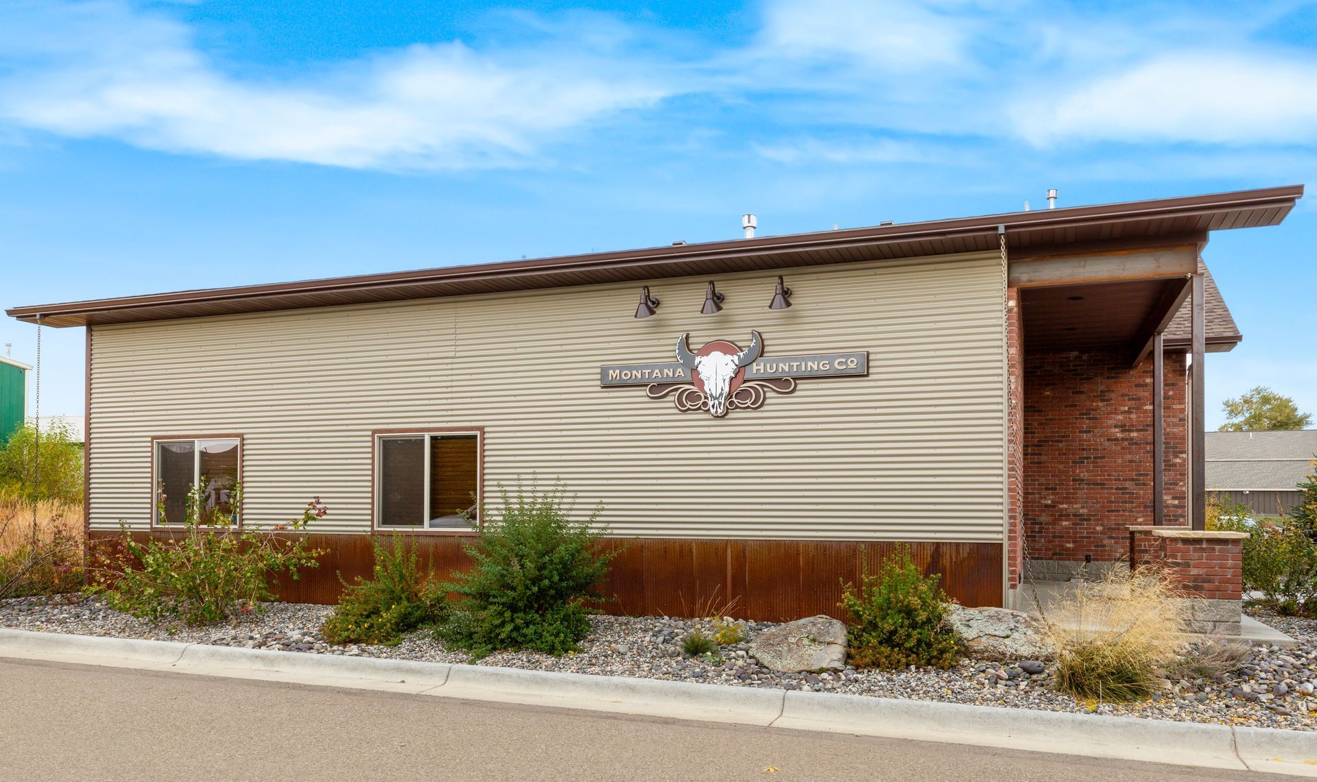 A low, tan, modern building with a western-style sign, brick siding on the entrance, and desert landscaping.