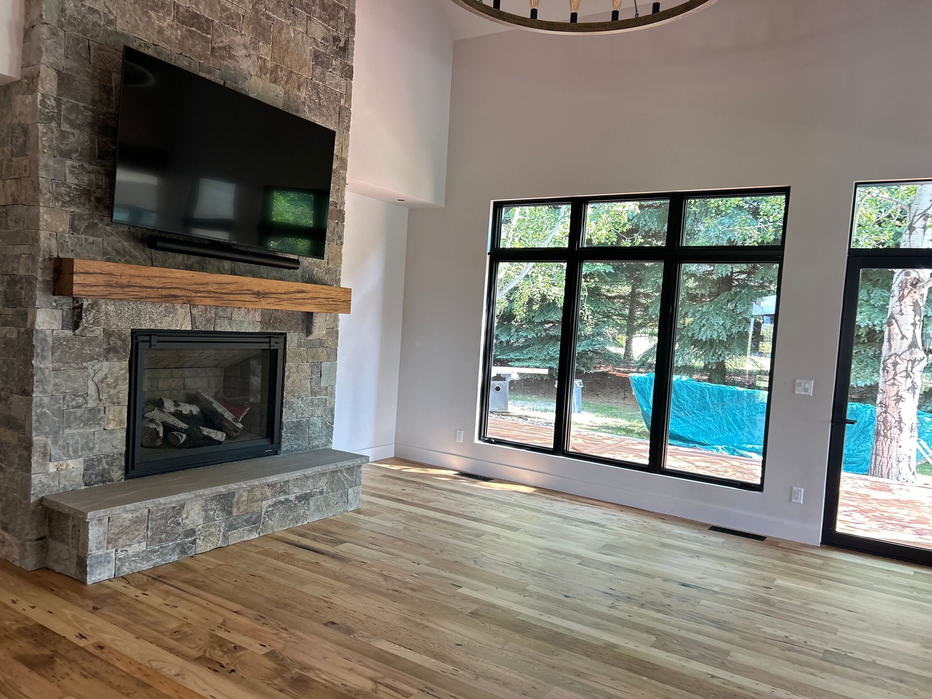 A brightly lit entryway featuring wood floors, a wooden staircase with black metal railings, and a modern geometric pendant.