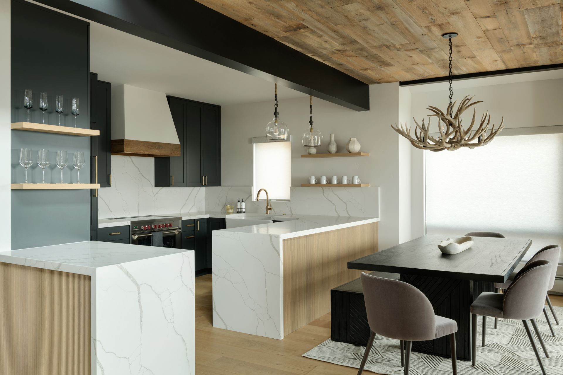 Modern open-concept kitchen and dining area with wood ceilings, stone fireplace, and marble-topped islands.