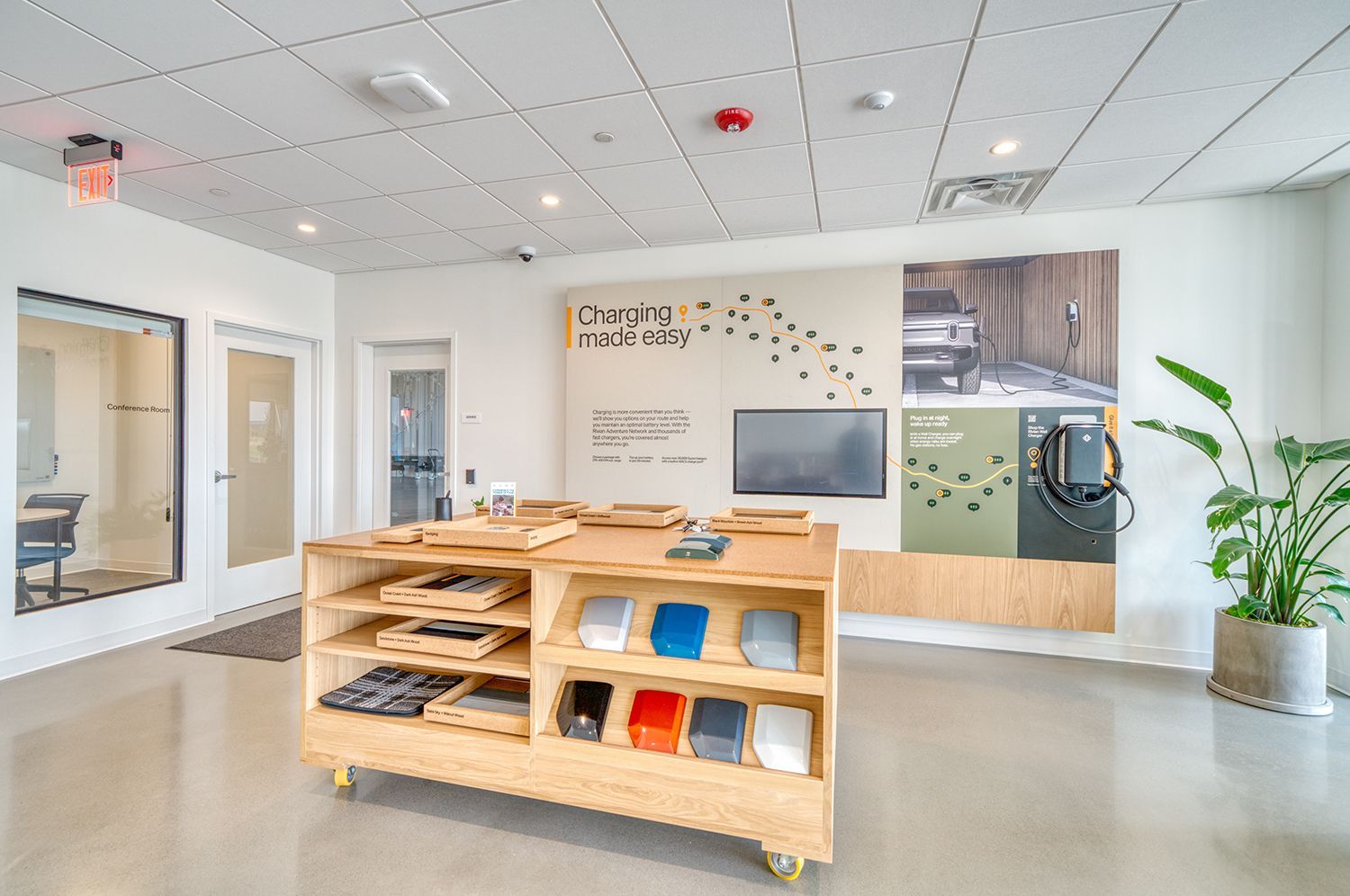 Modern waiting area with charging station, wooden display, and potted plant.