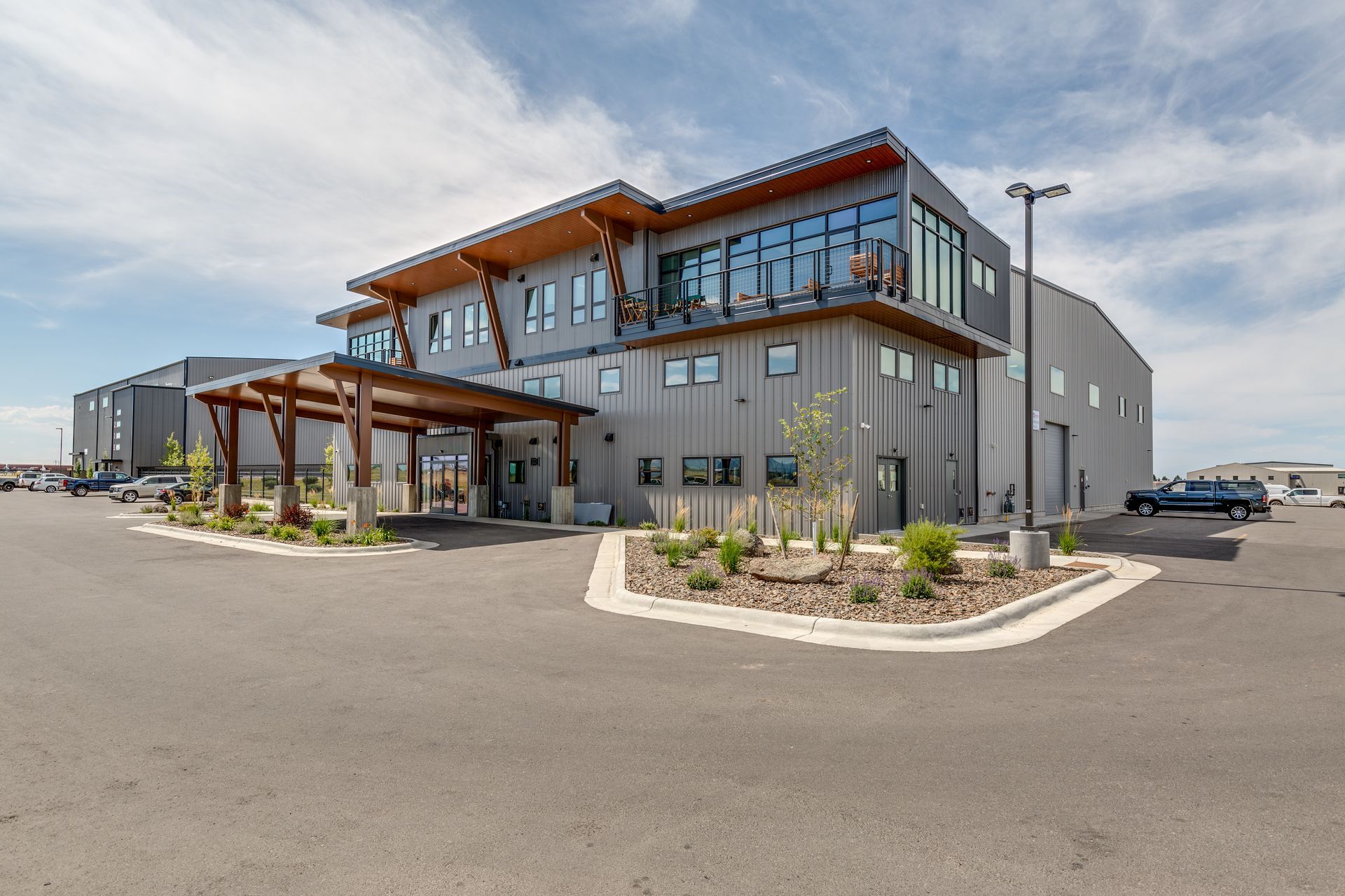 Modern commercial building with gray siding, a wooden portico, and blue sky.