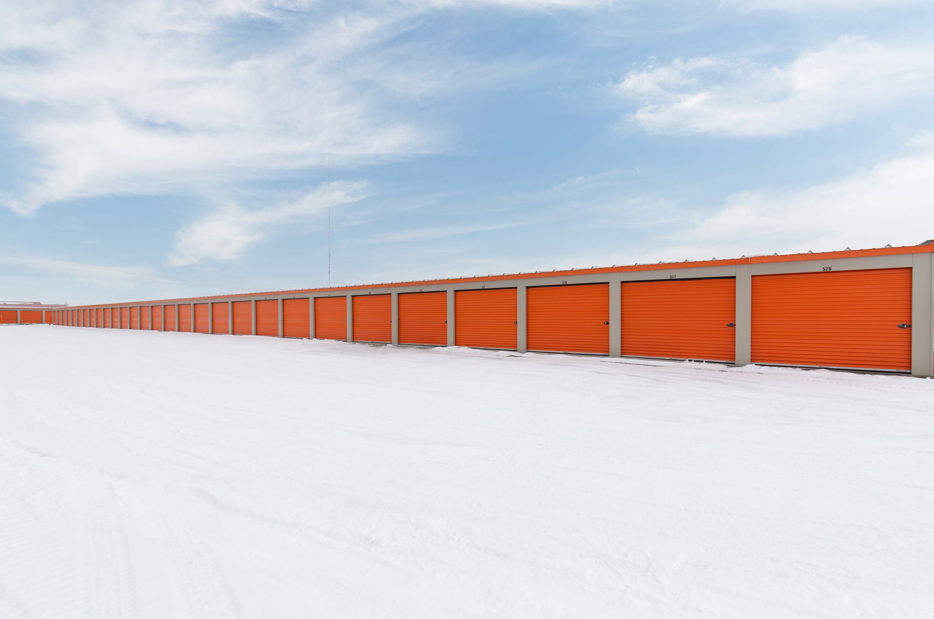 Row of orange storage units under a blue sky.