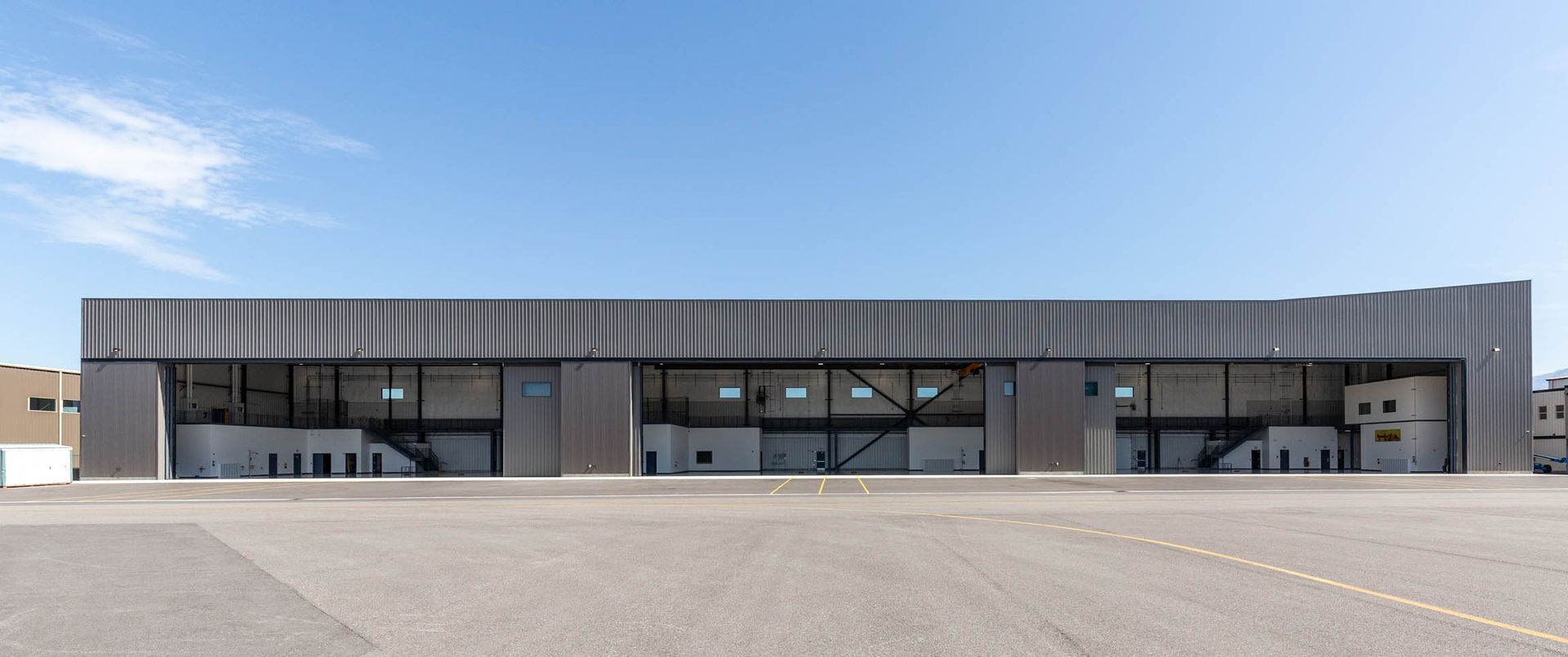 Modern building with ribbed metal siding and large glass windows under a clear blue sky.