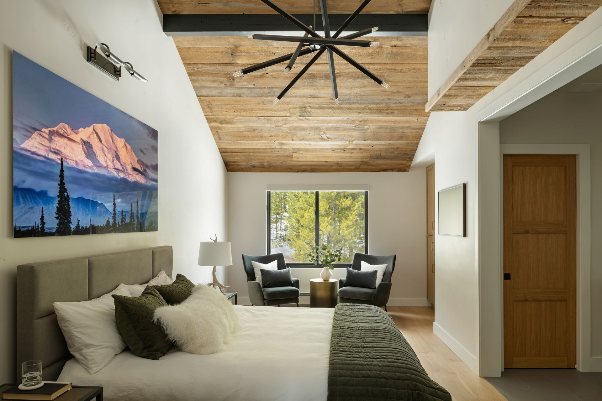 Bedroom with a wooden ceiling and large mountain landscape painting.