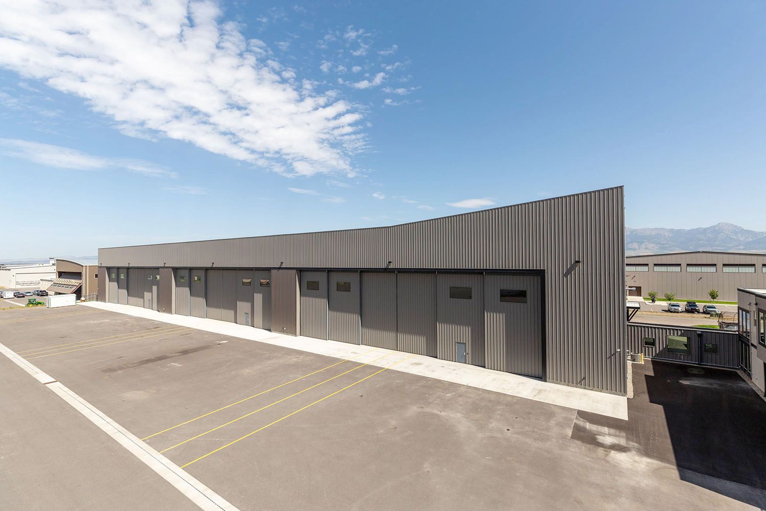 A long, dark gray metal storage building with multiple bay doors