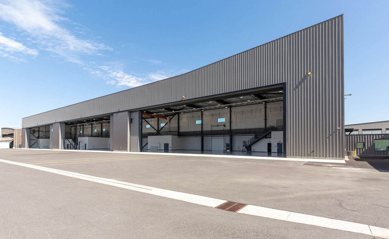 A modern, long industrial building with a sloped roof and ribbed metal exterior