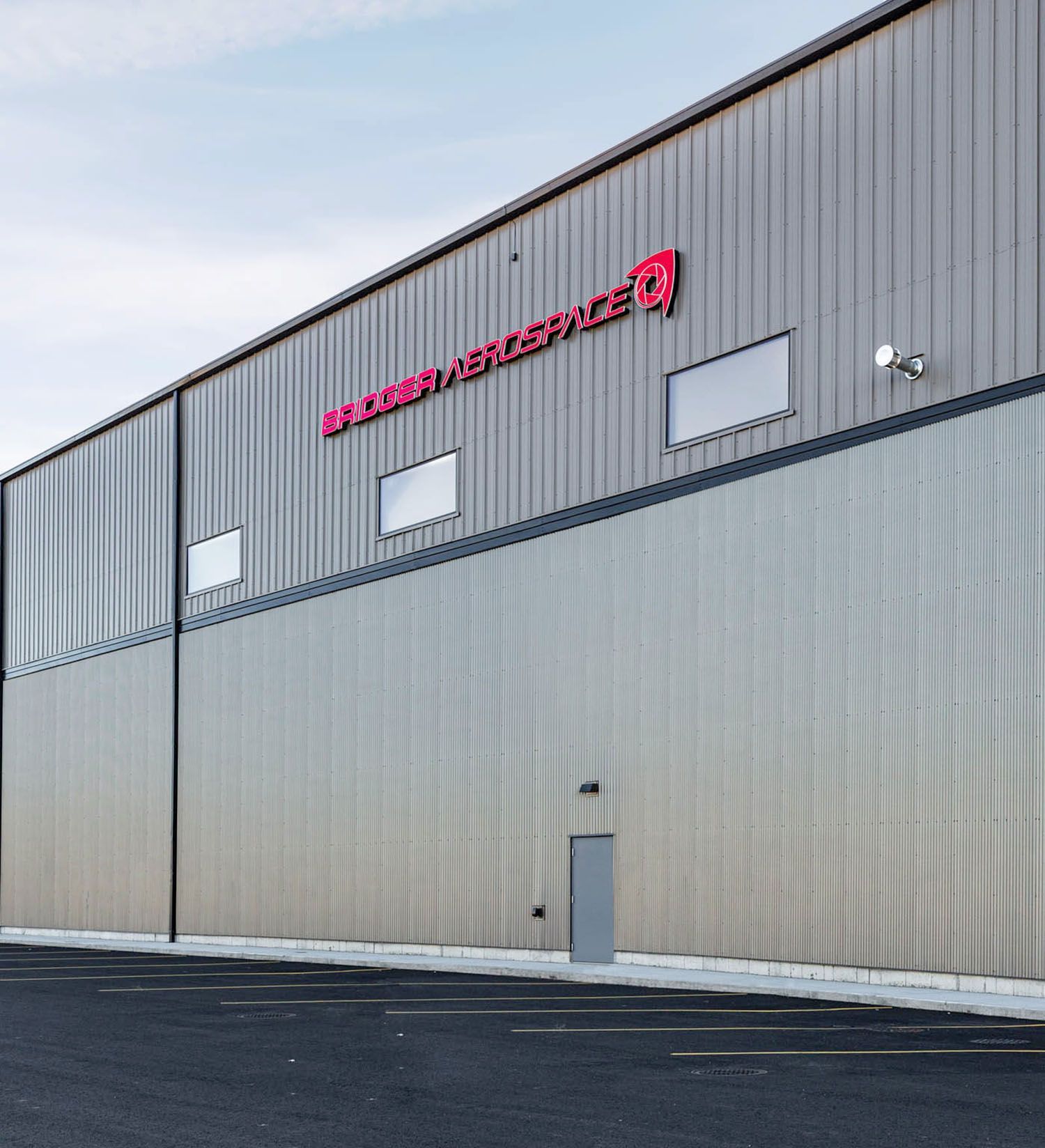 A metal-sided industrial building with red signage and three windows