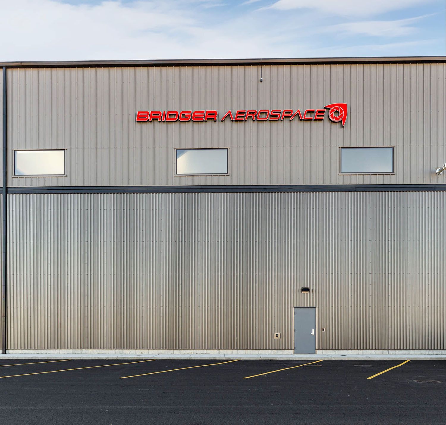 Exterior of a metal hangar building with light gray corrugated wall