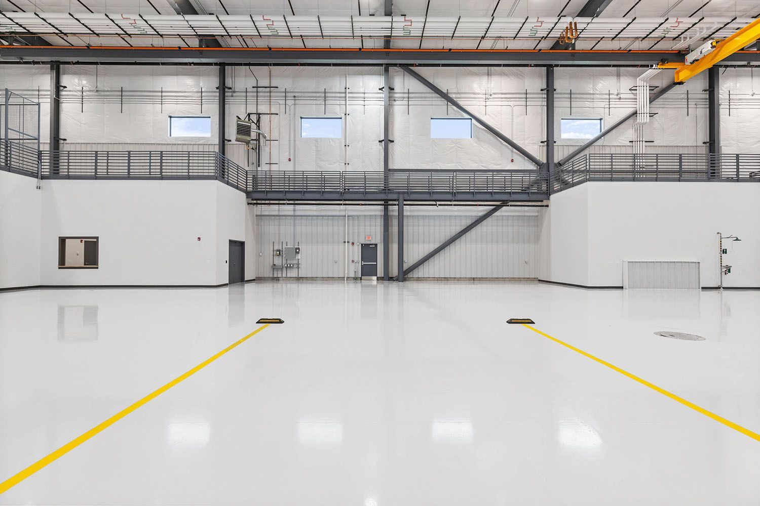 A spacious, white-walled industrial warehouse with a shiny floor