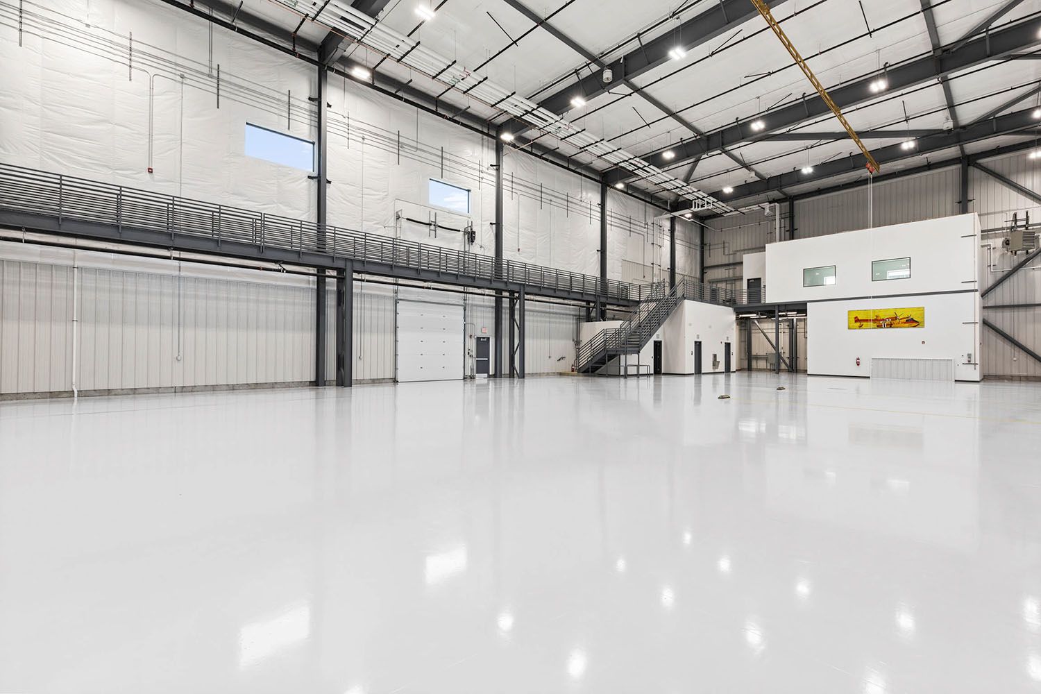 Empty, high-ceiling warehouse space with a glossy white floor