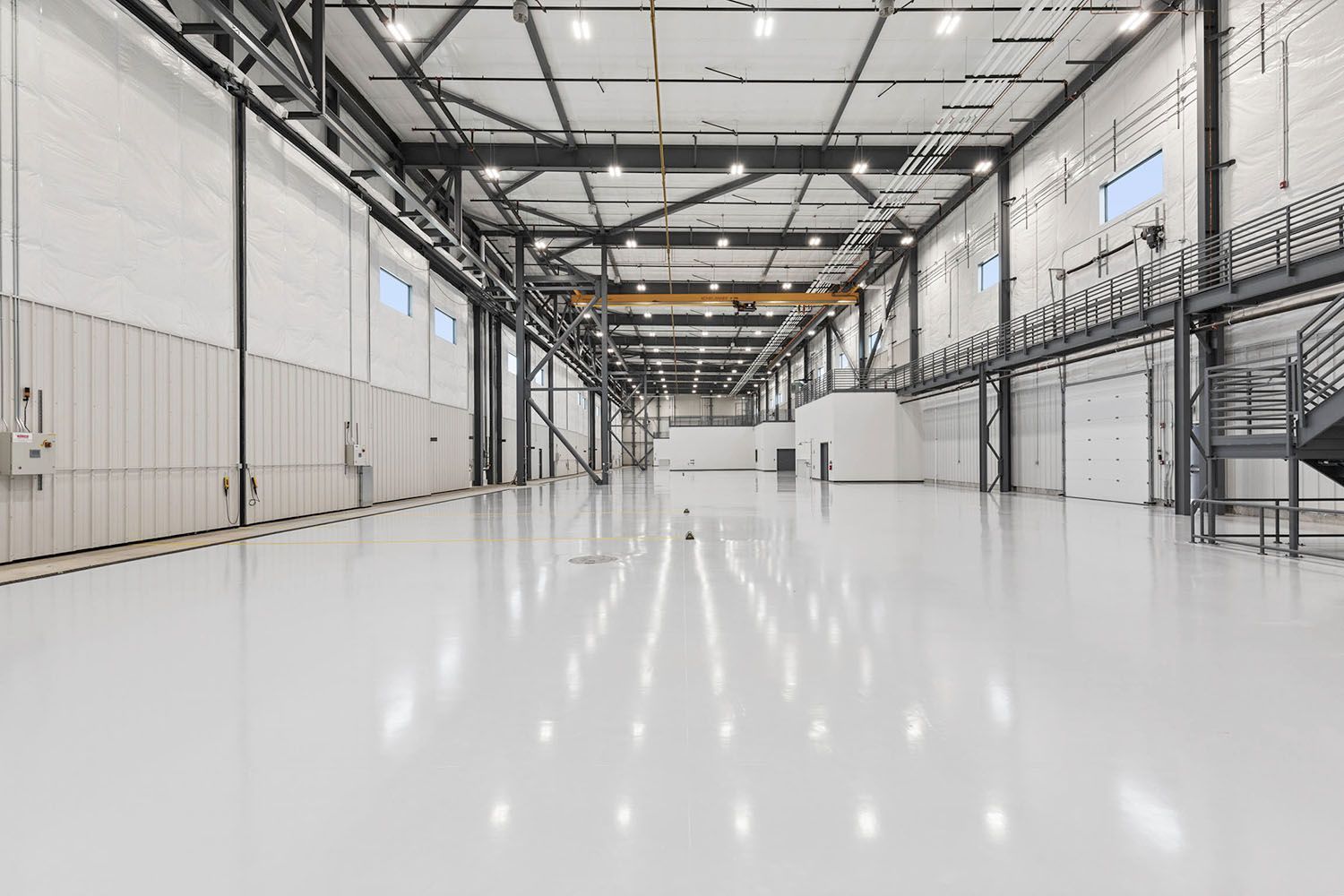 A spacious, empty industrial warehouse with white walls