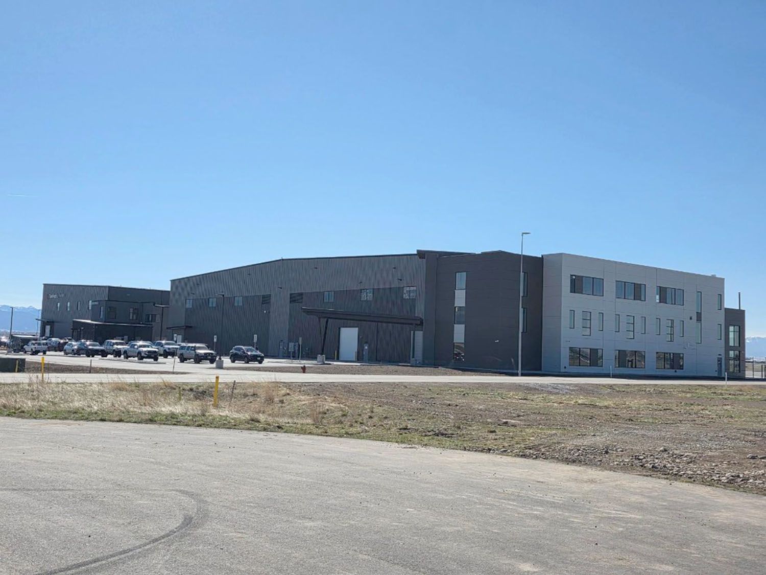A long, multi-story building with dark grey and white sections under a clear blue sky