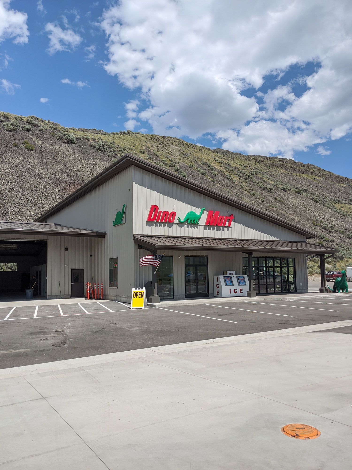 A convenience store sits at the base of a dry, rocky hill